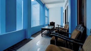 A room with blue walls, a wooden floor, a table, and two chairs. - Hotel O 94843 Syariah Hj. Lilis Sukabumi (Sukabumi)