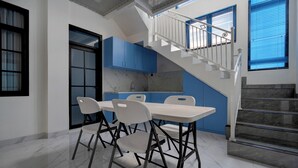 A modern kitchen with blue cabinets, a marble countertop, and a dining area with four white chairs. - Hotel O 94843 Syariah Hj. Lilis Sukabumi (Sukabumi)