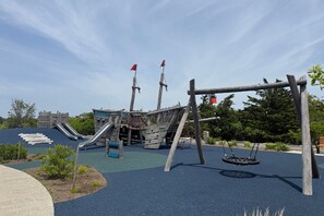 Un parque infantil con toboganes, columpios y una estructura de juegos con temática pirata.