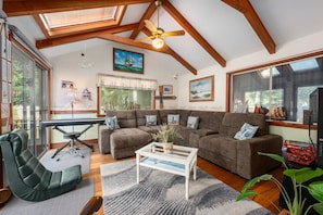 A spacious living room with a sectional sofa, a glass coffee table, and a ceiling fan. - Life's Better at Marshside Madness! (West Yarmouth)