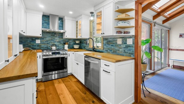 A modern kitchen with white cabinets, a stainless steel stove, and a dishwasher. - Life's Better at Marshside Madness! (West Yarmouth)