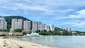 A coastal cityscape with high-rise buildings, a beach, and boats. - Seahome Boutique Hotel (Tanjung Bungah)