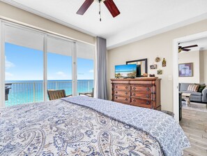 A bedroom with a large bed, a dresser, a television, and a balcony with a view of the ocean. - ☀️Gulf FRONT-Pools+Hot Tub-Beach Service-Emerald Isle 1406☀️ (Panama City Beach)