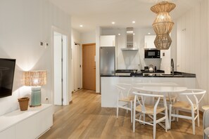 Eine moderne Küche mit einer zentralen Kochinsel, weißen Stühlen und einem Fernseher auf einem Schrank.
