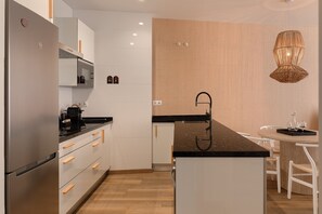 Eine moderne Küche mit einer zentralen Kochinsel, Edelstahlgeräten und einem Essbereich mit Tisch und Stühlen.