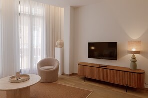 A modern living room with a round table, a cushioned chair, a wooden console, a flat-screen TV, and a lamp. - Souvirón de Torres II (Málaga)