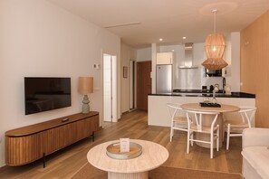 A modern living room with a flat-screen TV, a wooden console, a round coffee table, and a dining area with a white table and chairs. - Souvirón de Torres II (Málaga)