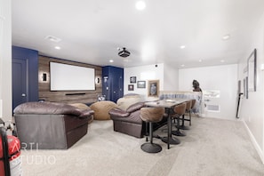 A home theater room with a large screen, leather recliner seating, a dining table with chairs, and a projector. - Private residential vacation home nestled in the native Navajo Sandstone rocks of Sand Hollow enjoy this one of a kind experiences.  4 Br, 3 bath rental that sleeps 10 with ease - themed and ready to enjoy! (Hurricane)