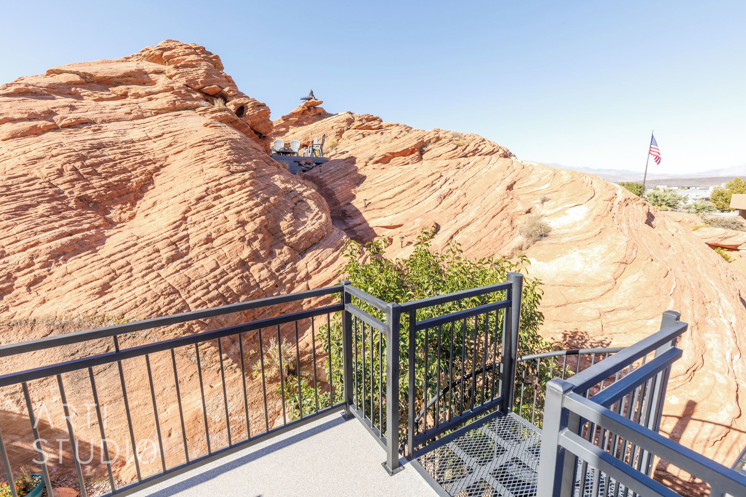 A staircase leading to a viewing platform with a railing, overlooking a rocky landscape with an American flag.