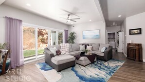 Ein modernes Wohnzimmer mit einem Ecksofa, einem Deckenventilator und einem großen Fenster mit violetten Vorhängen.