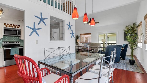 Una cocina moderna con microondas, horno y una mesa de comedor de vidrio con sillas.