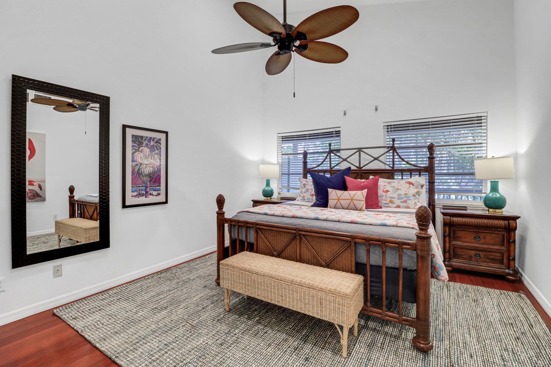 A bedroom with a wooden bed, a large mirror, and a ceiling fan.