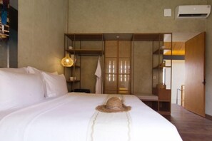 A bedroom with a bed, a wardrobe, a hanging light fixture, and a door. - Umahan Sanur (Bali)