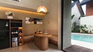 A modern kitchen with a built-in refrigerator, a wooden island with a fruit bowl, and a hanging light fixture. - Umahan Sanur (Bali)