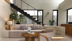 A modern living room with a sofa, coffee table, and a staircase. - Umahan Sanur (Bali)