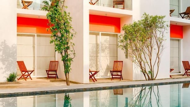 A modern building with a glass pool, wooden chairs, and potted plants. - Hotel J, Unawatuna (Unawatuna)