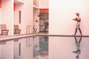 A pool area with a ladder, two lounge chairs, and a person carrying trays. - Hotel J, Unawatuna (Unawatuna)