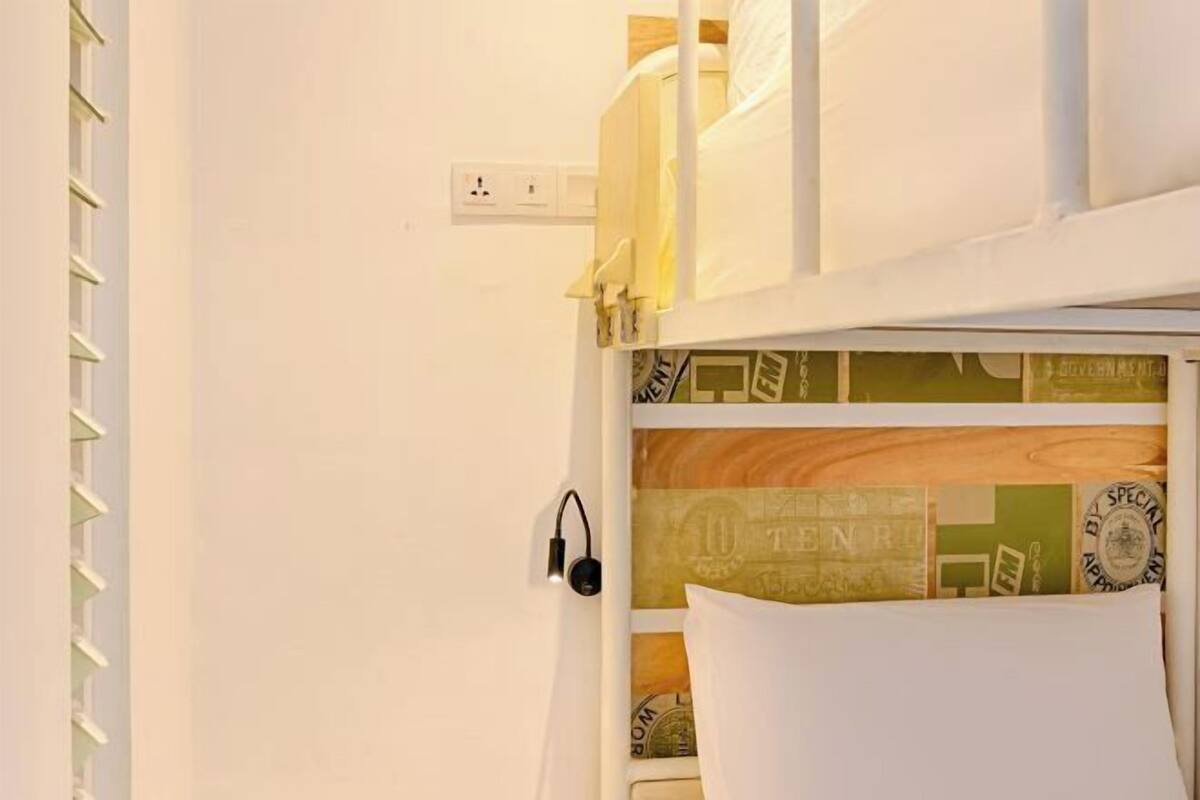 A bunk bed with a headboard featuring a vintage design, a power outlet, and a wall-mounted speaker.