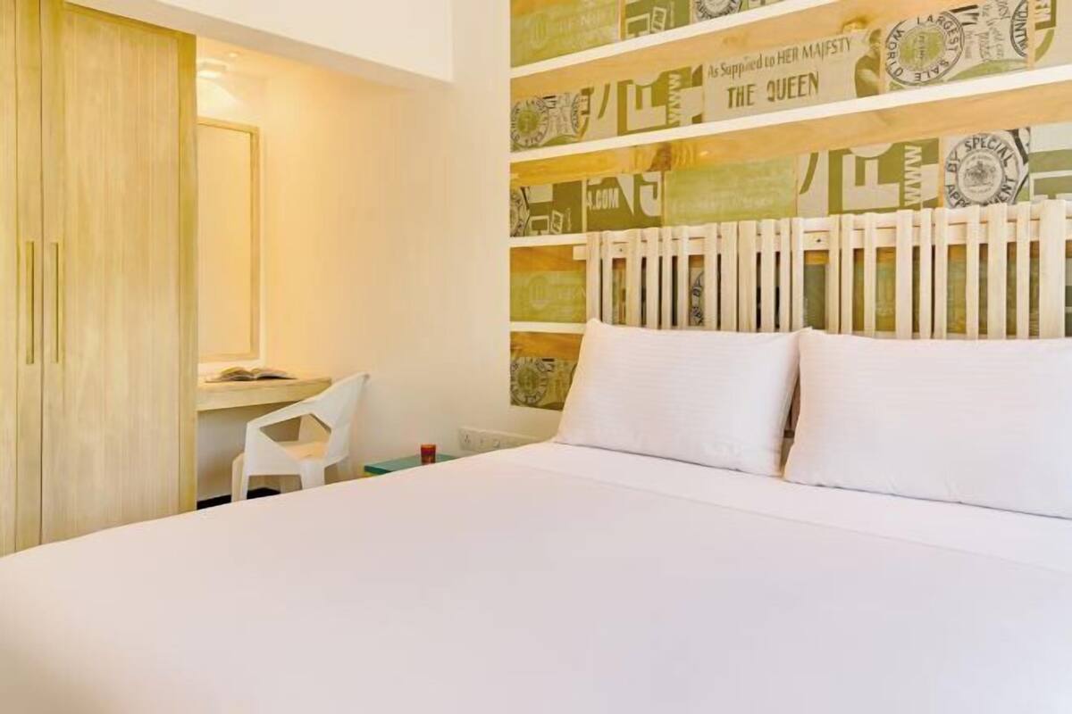 A bedroom with a bed, a desk, and a chair.
