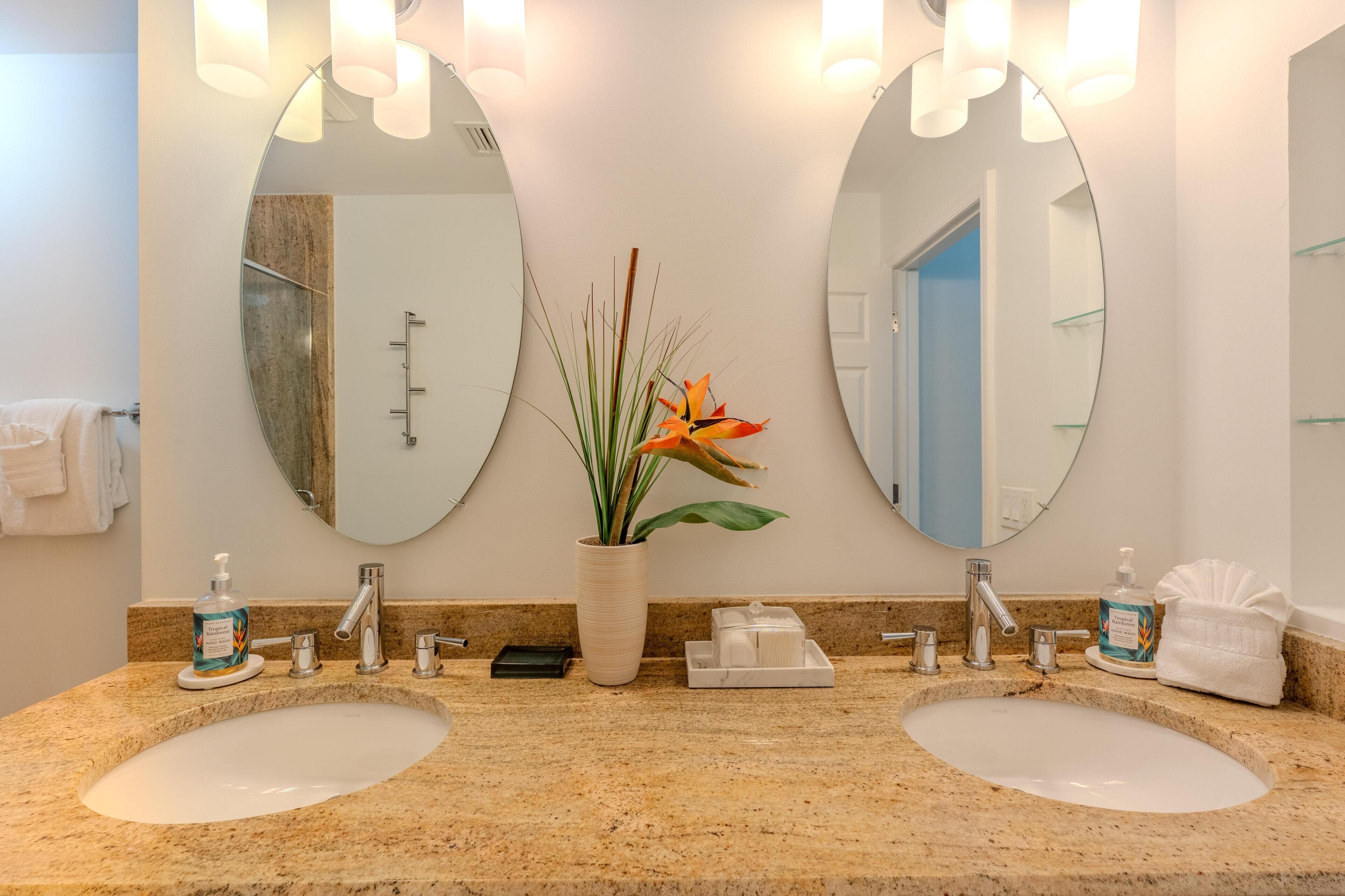 Une salle de bain avec deux lavabos, un grand miroir et une plante en pot.