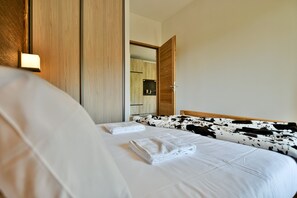 Ett hotellrum med en säng, en garderob i trä och en spegel.