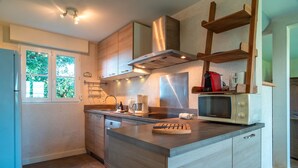 Una cocina moderna con armarios de madera, una campana extractora de acero inoxidable, un microondas y una isla integrada con tabla de cortar.