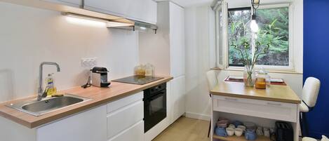 A compact kitchen with a wooden countertop, a built-in oven, and a window with a view of greenery.