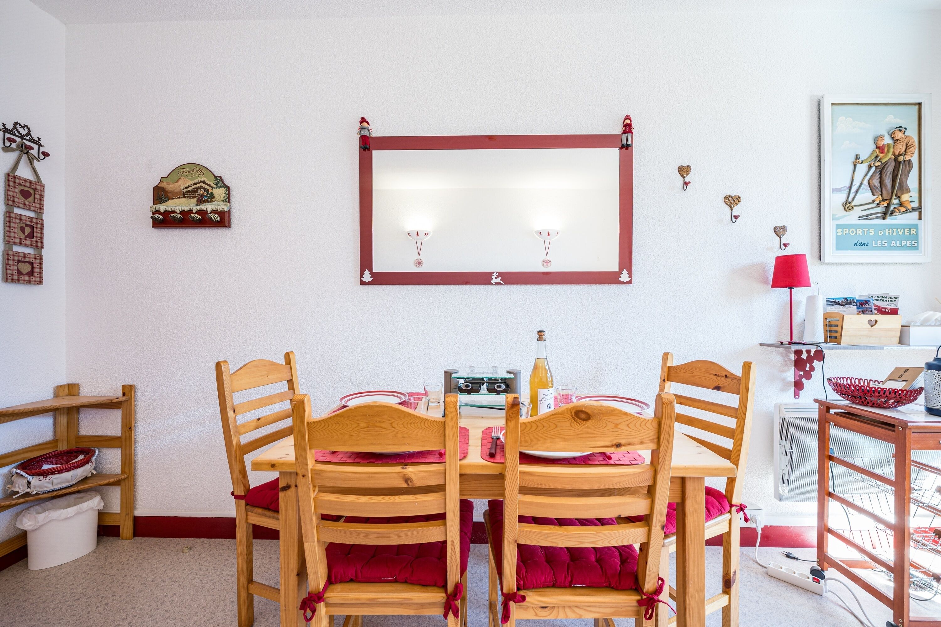A dining area with a wooden table and chairs, a mirror on the wall, and a framed picture.