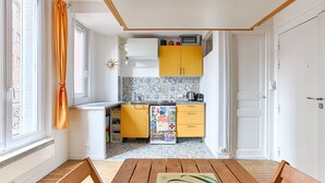 Eine kleine Küche mit gelben Schränken, einem Kühlschrank und einer Mikrowelle.