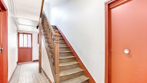 Eine Treppe mit Holzbalken und Geländer, die zu einer Tür mit strukturierter Wand führt.