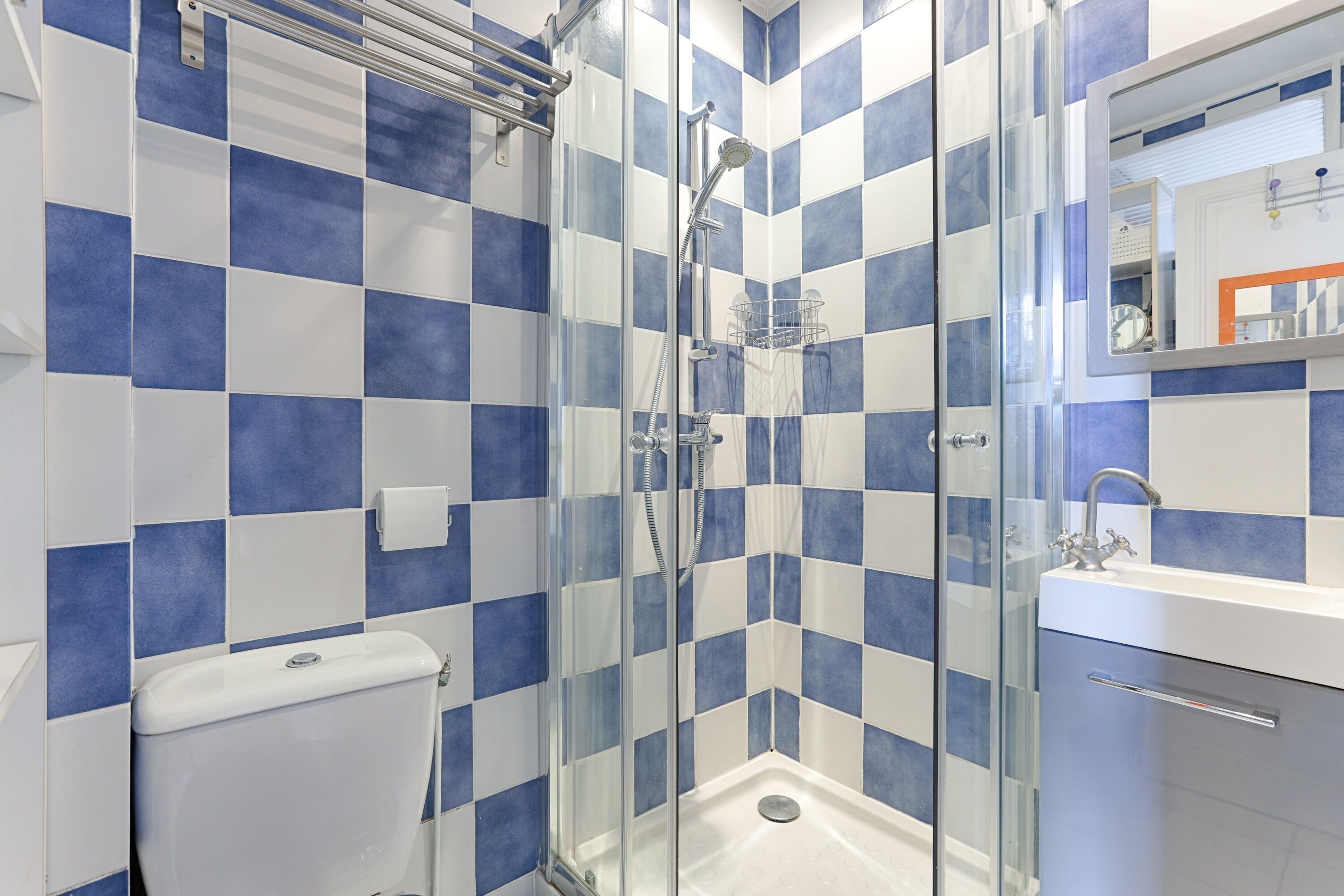 Ein Badezimmer mit Duschkabine, Toilette und Waschbecken mit Spiegel darüber.