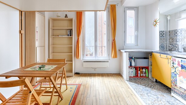 Ein kompakter Wohnraum mit Essbereich, einer Küche und einem Fenster mit Vorhängen.
