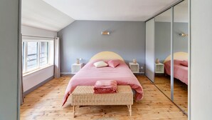 Ein Schlafzimmer mit einem Bett, einer Bank, einem Spiegel und einem Fenster.
