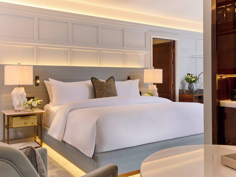 A hotel room with a large bed, two bedside tables, a nightstand, and a wooden wardrobe.