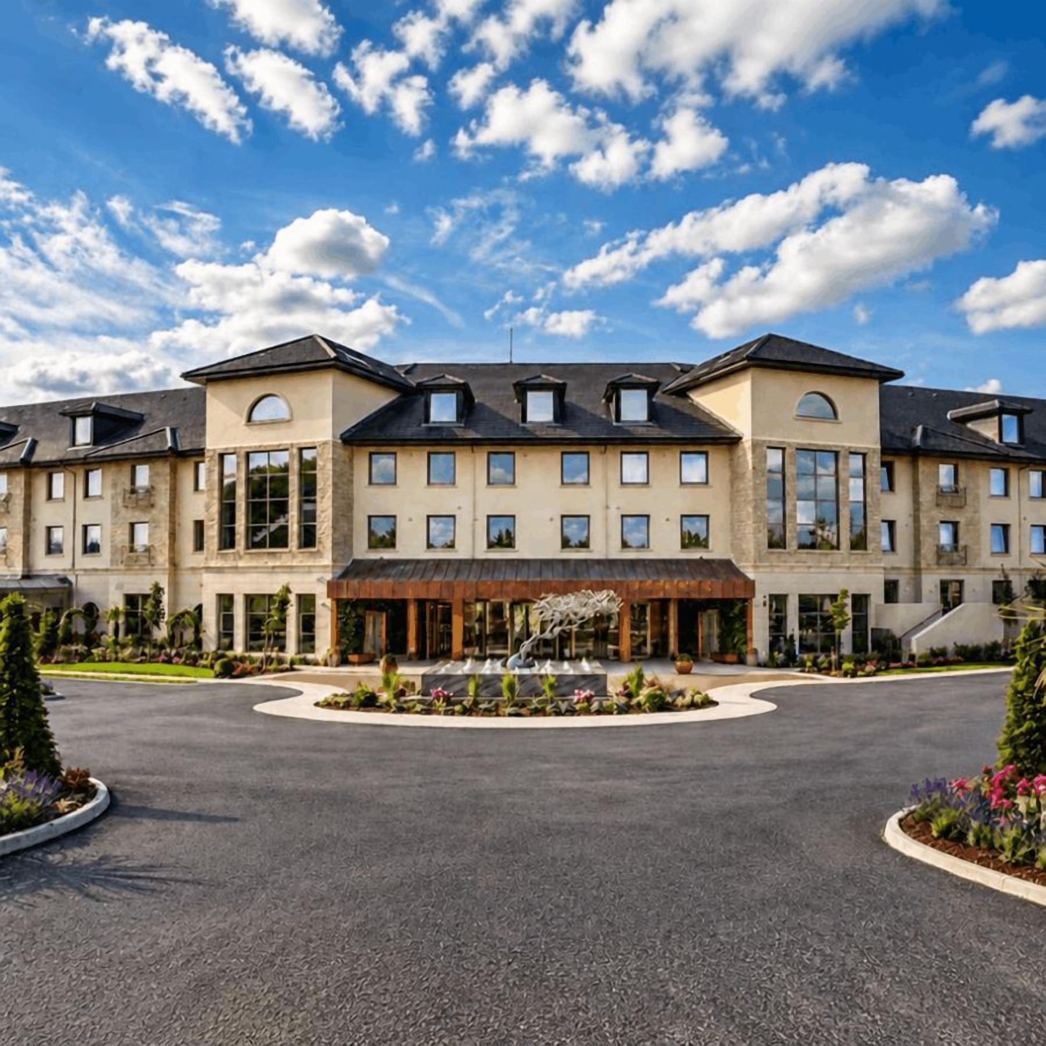 A large hotel with multiple floors, a central courtyard with a fountain, and a clear sky.