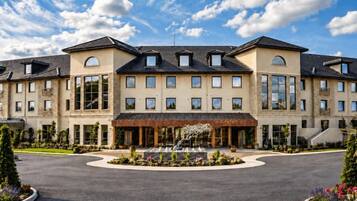 A large hotel with multiple floors, a central courtyard with a fountain, and a clear sky.