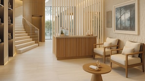 Een moderne lobby met een houten receptiebalie, een zithoek en een trap.