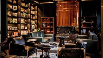 A modern lounge area with leather sofas, a marble coffee table, and bookshelves filled with books and decorative items.