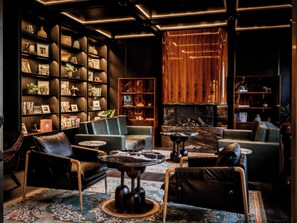 Un área de estar moderna con sofás de cuero, una mesa de centro de mármol y estanterías repletas de libros y objetos decorativos.
