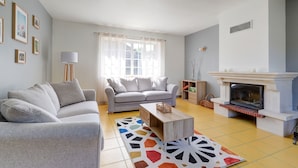 Una sala de estar con dos sofás grises, una mesa de centro, una chimenea y una alfombra colorida.
