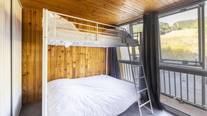 Habitación con literas, paredes de madera y un ventanal con vistas al exterior.