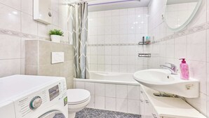 A modern bathroom with a toilet, a washing machine, a bathtub, and a sink. - Ida - Bergheim near Cologne (Bergheim)