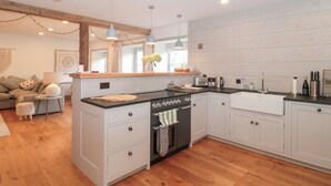 Una cocina moderna con armarios blancos, una isla central y un comedor con sofá y mesa.