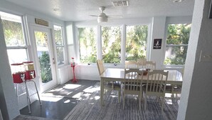 A sunlit room with a dining table and chairs, large windows, a ceiling fan, and a red floor lamp. - Weeki Wachee, Florida  Entire Home on Natural Spring - 2 Bed 2 Bath (Weeki Wachee)