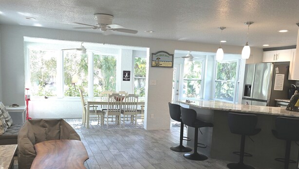 A spacious kitchen with a dining area, large windows, and a ceiling fan. - Weeki Wachee, Florida  Entire Home on Natural Spring - 2 Bed 2 Bath (Weeki Wachee)