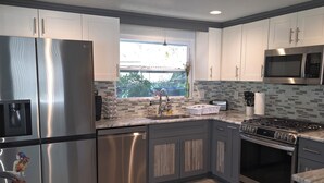 A modern kitchen with stainless steel appliances, a window with a view, and a tiled backsplash. - Weeki Wachee, Florida  Entire Home on Natural Spring - 2 Bed 2 Bath (Weeki Wachee)