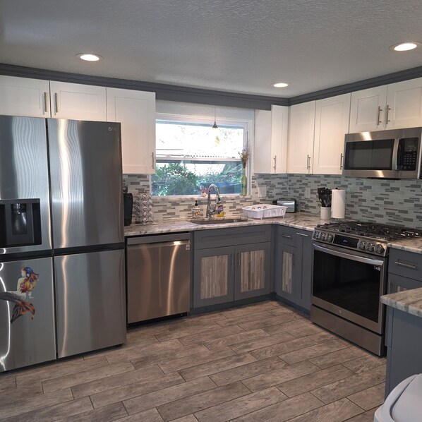 A modern kitchen with stainless steel appliances, a window with a view, and a tiled backsplash. - Weeki Wachee, Florida Entire Home on Natural Spring - 2 Bed 2 Bath (Weeki Wachee)