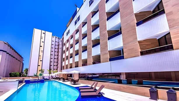 A hotel with a swimming pool, multiple balconies, and outdoor seating areas. - Gold Flat  (João Pessoa)