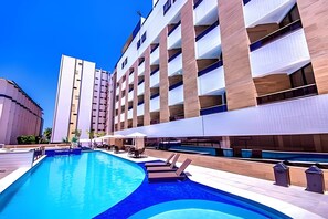 A hotel with a swimming pool, multiple balconies, and outdoor seating areas. - Gold Flat  (João Pessoa)