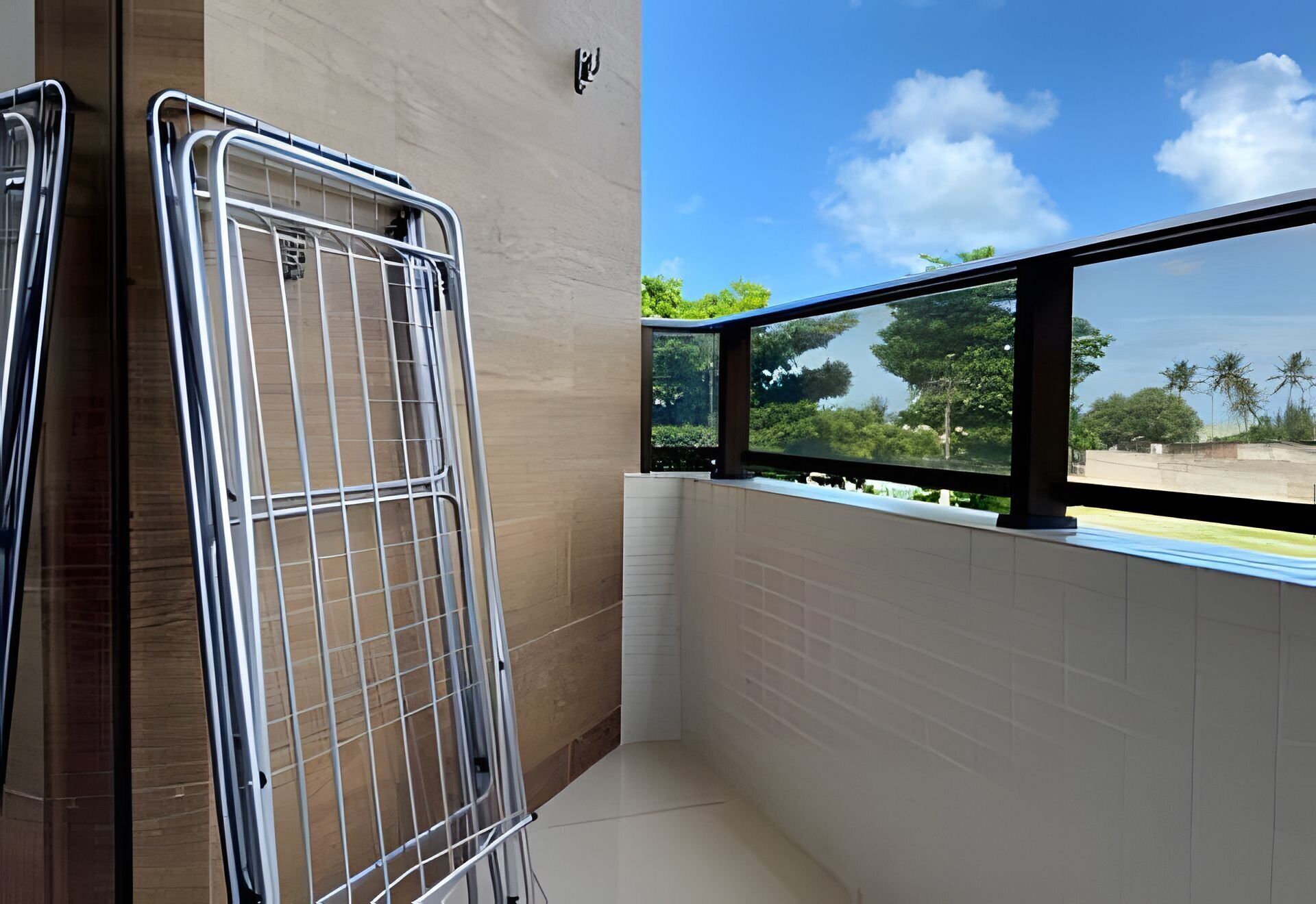Ein Balkon mit Metallgeländern, Blick auf Bäume und einen klaren Himmel.